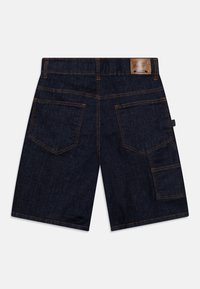 Tmavé denim šortky s rovnýcm střihem, které mají dvě zadní kapsy a rozšiřitelnou postranní kapsu. Kontrastní stehy zdůrazňují švy.