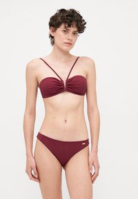 Burgunderfarget ribbestrikket bikiniset med en samlet bandeau-top og tynne stropper, matchende lavt høyde-biker med en subtil gullaccent.