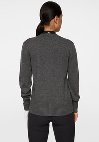 Grå stickad tröja med rund halsringning, ribbad nederkant och ärmslut, med en slät textur och åtsittande silhuett. Inga synliga logotyper eller mönster.