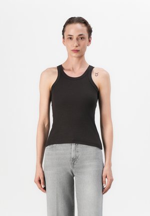 Must mustriba tank top kõrge kaelusega ja laiade rihmadega, koos heledate hallide laiade pükstega, valge tausta ees.