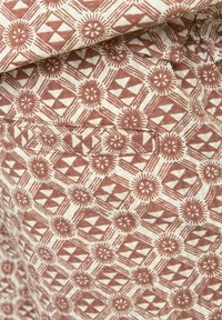 Tissu en coton à motifs présentant un design géométrique marron sur un fond crème clair, avec des motifs floraux et triangulaires.