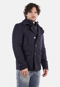 Cappotto doppiopetto blu navy con sei bottoni, tessuto misto lana, colletto a rever, due tasche frontali e vestibilità strutturata.