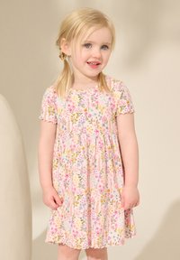 Robe fleurie avec un fond rose pâle orné de fleurs multicolores. Manches courtes et jupe froncée avec un ourlet festonné.