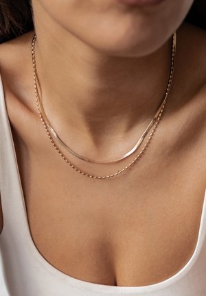 Gold-tone layered necklaces featuring a smooth, curved chain and a beaded chain; metallic sheen and delicate, lightweight design.