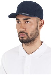 Tumed müts, millel on kumer viskitus ja mis on valmistatud tekstuuritud kangast. Mütsil on viskituse ääres peen hõbedane detail. Kanda valge polo särgiga.