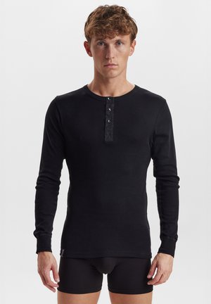 Sort langærmet henley skjorte lavet af blødt stof med rund halsudskæring, tre-knaps placket og tætsiddende ærmer.