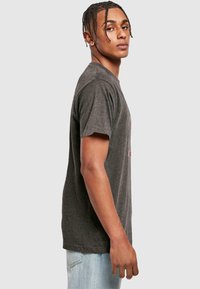 Dunkelgraues Baumwoll-T-Shirt mit Rundhalsausschnitt, kurzen Ärmeln und lässiger Passform. Mit grafischem Druck auf der Vorderseite.