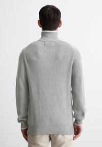 Gray ribbed sweater with a high neck, featuring a white inner collar. Long sleeves and a relaxed fit, with a textured knit pattern.