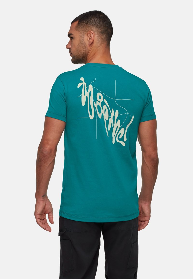 Teal bomulds T-shirt med et cremet abstrakt design på ryggen. Korte ærmer og rund hals, med en tætsiddende pasform.