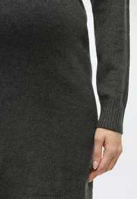 Σκούρο γκρι πλεκτό φόρεμα με ριμπ μανσέτες στους καρπούς. Υφή στο ύφασμα· εφαρμοστό σχέδιο που αναδεικνύει τη σιλουέτα.