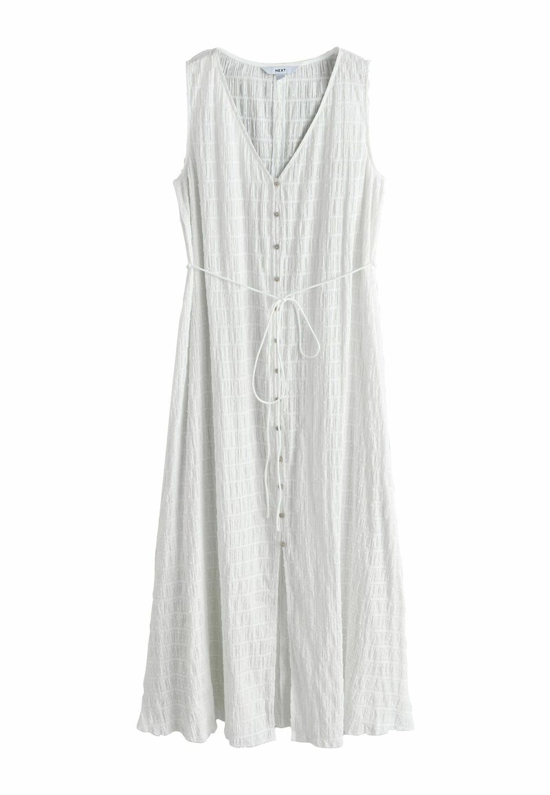 Robe blanche sans manches avec un col en V, tissu texturé, ceinture élastique à la taille et fermeture à boutons sur le devant. Silhouette longue et fluide.