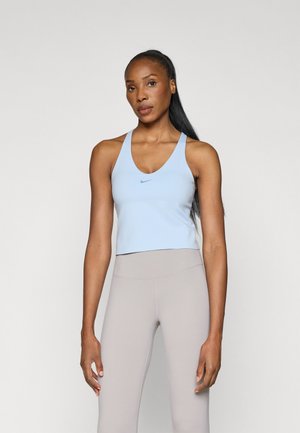 Light blue athletic crop top with a v-neck and wide straps, featuring a small Nike logo. Paired with high-waisted beige leggings.