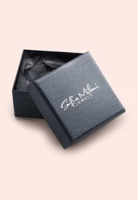 Scatola di gioielli nera con superficie texturizzata, dotata di un logo bianco "Sofia Milani Jewels" sul coperchio e della carta velina nera all'interno.