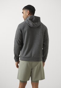 Grå hættetrøje med tekstureret overflade, der har raglanærmer. Matchet med lysegrønne shorts, der er designet til komfort og bevægelse.