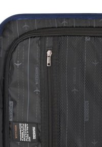 Interno di una borsa da viaggio nera con tasca a rete, cerniera argentata e disegni stampati di aerei e piste. Presenta etichetta del marchio e dettagli del motivo.