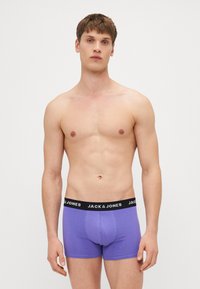 Boxeri scurți din bumbac violet, cu un tiv negru, având numele brandului "JACK & JONES" scris cu litere albe. Textură netedă și design mulat.