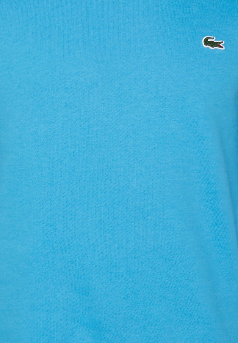 T-shirt in cotone blu con una texture liscia e un piccolo logo di coccodrillo verde sul lato sinistro del petto. Orlo dritto, maniche corte.