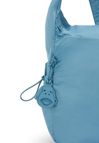 Blå nylonväska med en slät textur, utrustad med en unik dragkedja formad som en apa i matchande blått, samt en elegant, rundad siluett.