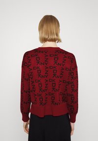 Burgunderfarbener Pullover mit schwarzem "DKNY" Logo-Muster, gestrickter Textur, lockerer Passform und geripptem Saum. Die Rückansicht zeigt die Kontinuität des Logos.