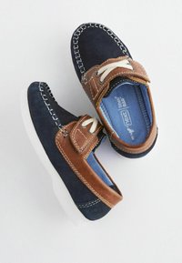 Marineblaue Wildlederschuhe mit beige Lederakzenten und weißen Gummisohlen. Mit Schnürverschluss und gestickten Details entlang der Kante.