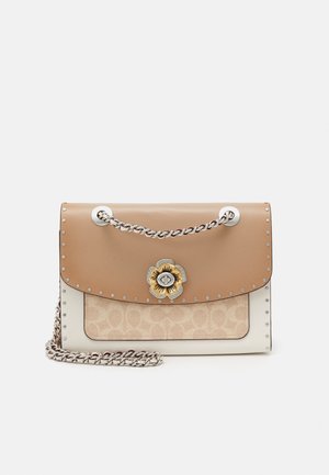Torba skórzana w kolorze brązowym z fakturowanym beżowym przodem, srebrnym łańcuszkiem oraz charakterystycznym kwiatuszkiem jako elementem ozdobnym. Małe ćwieki zdobią krawędź torby.