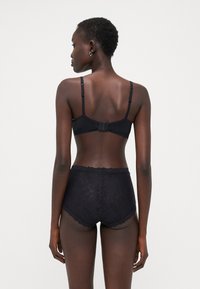 Black lace bra and high-waisted panties set with scalloped edges, adjustable straps, and floral pattern detail on the fabric.