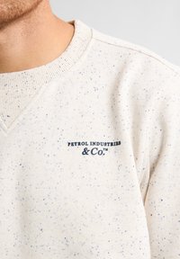 Felpa beige con motivo a macchie blu, colletto a coste e logo "PETROL INDUSTRIES & Co." in blu scuro sul petto.