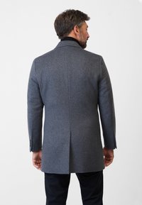 Grijze wollen jas met een inkeping kraag en een enkele achterventilatie. Voorzien van knoopsluiting bij de manchetten en een strak, gestructureerd silhouet.