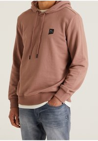 Sudadera con capucha en color rosa empolvado, fabricada en un tejido suave. Presenta un parche de logo cuadrado negro, cordones y puños y dobladillo acanalados.