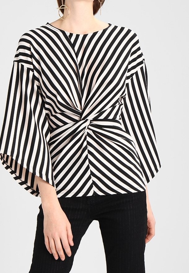 Mustat ja valkoiset raidalliset paita, jossa on solmittu yksityiskohta vyötäröllä, leveät hihat ja pyöreä kaula-aukko. Sileä kangas.