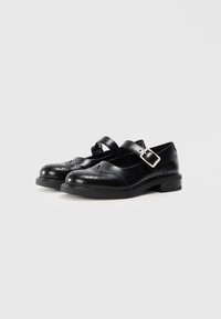 Scarpe Mary Jane in pelle nera con punta arrotondata, dettagli brogue, cinturino regolabile e tacco basso a blocco. Superficie liscia e design classico.