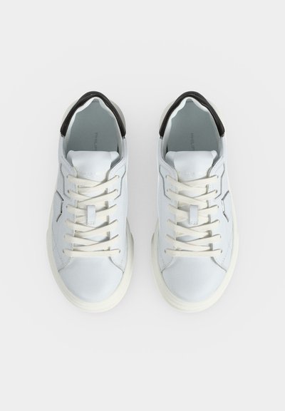Paire de baskets blanches à lacets avec des accents noirs au talon, vue de dessus sur un fond blanc uni.