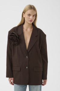 Brązowy oversize marynarka z dużą tkaninową różą ozdobną na lewym ramieniu, z dwoma przednimi guzikami i kieszeniami z klapami.
