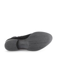 Zapato de ante negro con suela de goma texturizada, presenta un pequeño tacón y la marca Gabor en la plantilla. Diseño suave y aerodinámico.