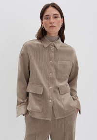 Giacca in corda beige con colletto, chiusura frontale a bottoni e quattro tasche; presenta una superficie texturizzata e una vestibilità comoda.