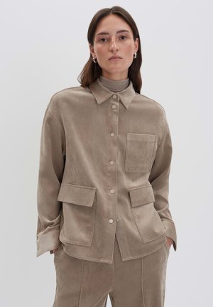 Veste en velours côtelé beige avec col, fermeture à boutons sur le devant et quatre poches ; présente une surface texturée et une coupe décontractée.