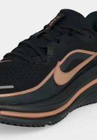 Μαύρο και χαλκερό παπούτσι τρεξίματος Nike με δίχτυ, κλείσιμο με κορδόνια και μαξιλαρωμένη σόλα, μέγεθος 12 ορατό στην ετικέτα της γλώσσας.