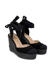 Sandales à talons compensés noires avec une tige en daim, plateforme tissée noire et liens à la cheville. Présente un détail de bout rond tissé.