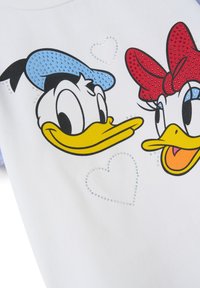 Camiseta de algodón blanca con ilustraciones de Donald y Daisy Duck, adornada con Rhinestones que forman corazones y acentos en azul y rojo.
