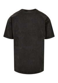 Camiseta de algodón negra con mangas cortas, escote redondeado y corte relajado. Acabado texturizado y lavado con costuras visibles.