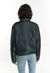 Giubbotto imbottito nero con colletto alto, design trapuntato, vita elastica e maniche a polsino, visto da dietro.