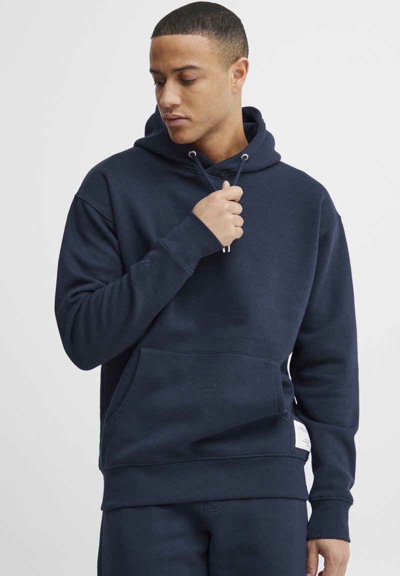 Sudadera azul marino con capucha, bolsillo tipo canguro, puños y cinturilla de canalé. Confeccionada con un tejido suave y texturizado.