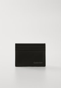 Portofel din piele neagră pentru carduri, cu multiple sloturi pentru carduri, textură netedă, cusături discrete și logo-ul argintiu "Calvin Klein" pe partea din față, în partea de jos.