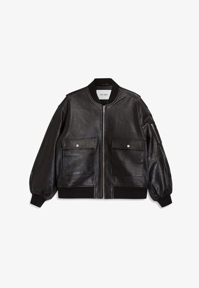 Giacca bomber in pelle nera con zip frontale, polsini a coste e due ampie tasche frontali. Presenta una superficie testurizzata e un design aderente.