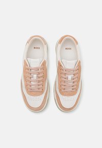 Sneakers con una toma superiore in pelle bianca e morbidi dettagli in suede pesca. Presentano lacci coordinati e un colletto imbottito. Area della punta perforata.