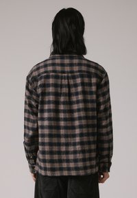 Camicia di flanella con un motivo a quadri navy scuro e chiaro, caratterizzata da un colletto, polsini con bottone e una vestibilità comoda. Tessuto testurizzato con un aspetto caldo.