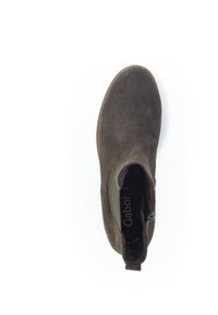 Hnědá semišová kotníková bota s elastickými bočními panely, zaoblenou špičkou a nízkým podpatkem. Na zadní straně je malá poutko pro snadné obouvání.