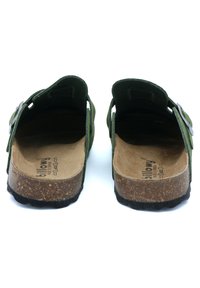 Sandales en daim vert avec un dos ouvert, semelle en liège et semelle en caoutchouc noir texturé. Comprend une boucle en métal pour un ajustement réglable.