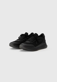 Baskets de sport noires en mesh et en matériau synthétique, avec une semelle texturée, un bout rond et un design traditionnel à lacets.