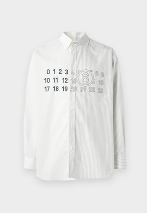 Chemise moitié blanche et moitié rayée avec un grand imprimé numérique et un graphique circulaire sur le côté gauche. Fabriquée en tissu de coton tissé.